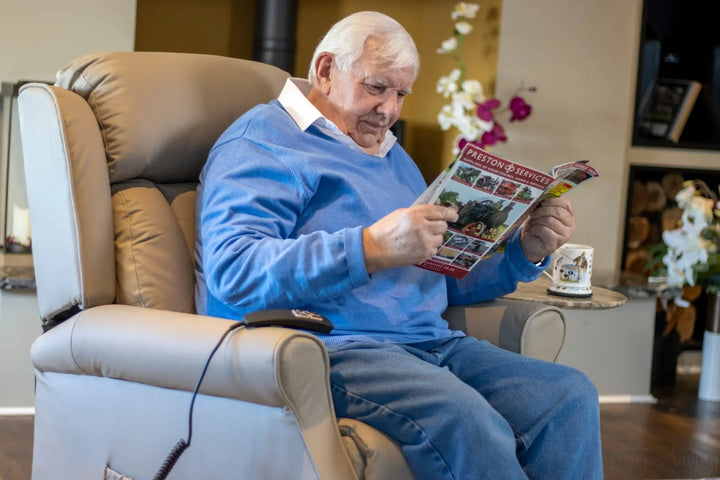 A man sitting in an armchair reading a magazine.
